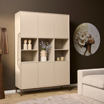 Vakkenkast Madison van Starfurn tegen een wand in een woonkamer, gevuld met boeken, manden en groen