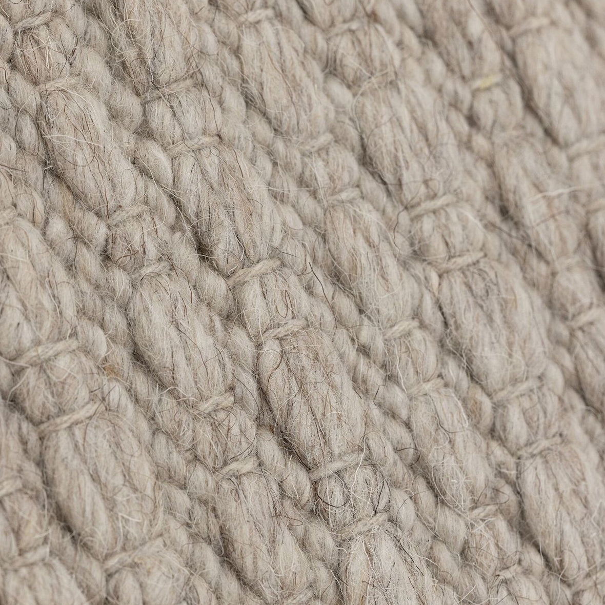 Vloerkleed Nirvana van MUST Living, detailfoto van de dikke gevlochten wolstructuur in beige