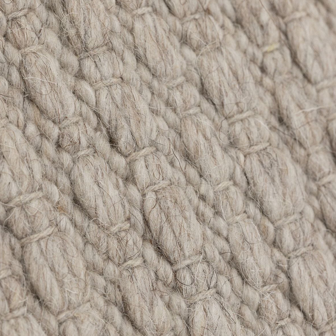 Vloerkleed Nirvana van MUST Living, detailfoto van de dikke gevlochten wolstructuur in beige