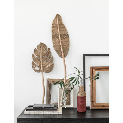 Wandblad Perzik Small van MUST Living, rotan wandpaneel in bladvorm boven een dressoir