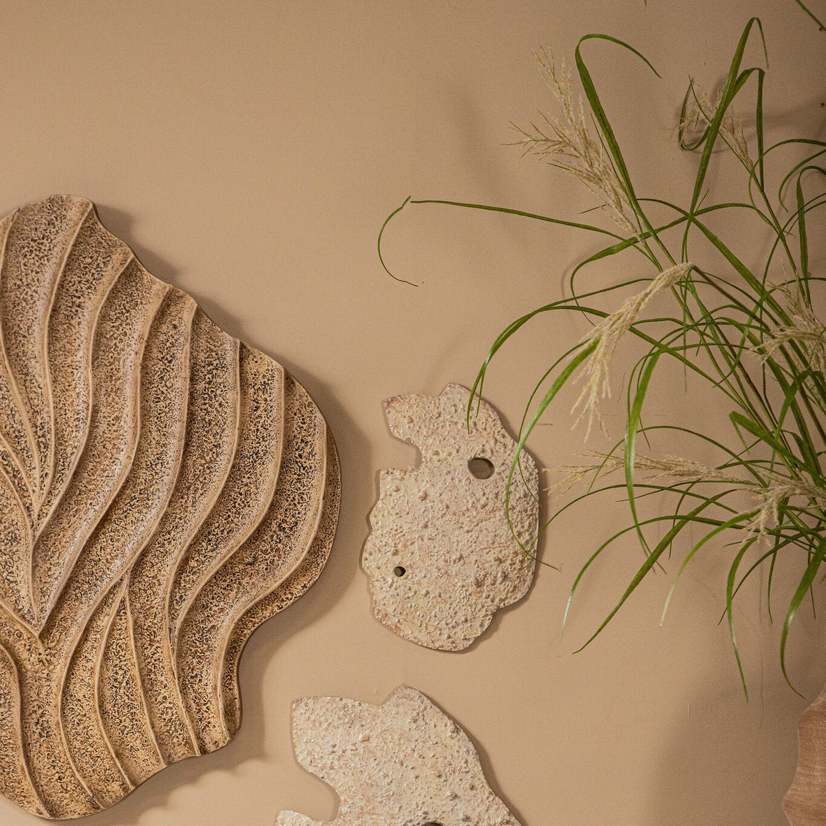 Zijaanzicht van het Abbie wandpaneel van PTMD aan de muur, het golvende beige reliëf vangt het licht